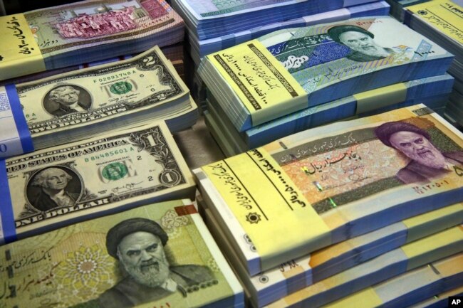 FILE- Iranian and U.S. banknotes are on display at a currency exchange shop in downtown Tehran, Iran, April 4, 2015. In recent months, Iran has been beset by economic problems despite the promises surrounding the 2015 nuclear deal it struck with world powers.