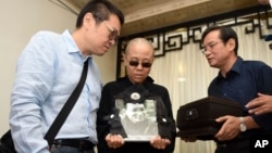 Liu Xia, wife of jailed Nobel Peace Prize winner and Chinese dissident Liu Xiaobo, holds a portrait of him during his funeral in Shenyang in northeastern China's Liaoning Province, July 15, 2017. The photo shows, from left to right, Liu Hui, younger brother of Liu Xia, Liu Xia and Liu Xiaoxuan, younger brother of Liu Xiaobo holding his cremated remains.