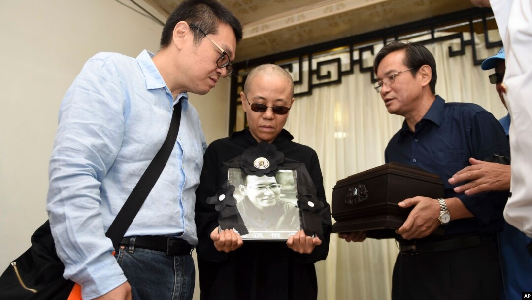 Lu Xia, istri dari pembangkang China dan pemenang penghargaan Nobel Perdamaian China yang ditahan, Liu Xiabo, memegang foto Lu Xiabo pada saat pemakaman Xiabo di Shenyang, di Provinsi Liaoning, timur laut China, 15 Juli 2017.
