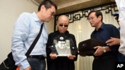 FILE - Liu Xia, wife of jailed Nobel Peace Prize winner and Chinese dissident Liu Xiaobo, holds a portrait of him during his funeral in Shenyang in northeastern China's Liaoning Province, July 15, 2017. 