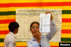 FILE - An election official shows a ballot paper as votes are counted at a polling station in Phnom Penh, July 28, 2013.