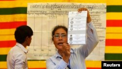 FILE - An election official shows a ballot paper as votes are counted at a polling station in Phnom Penh, July 28, 2013.