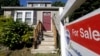 FILE - A "For Sale" sign hangs in front of a house in Walpole, Massachusetts.