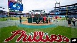 Los Filis de Filadelfia se reúnen alrededor de la jaula de bateo durante un entrenamiento de béisbol, el viernes 4 de octubre de 2024, en Filadelfia, antes de la Serie Divisional de la Liga Nacional contra los Mets de Nueva York.