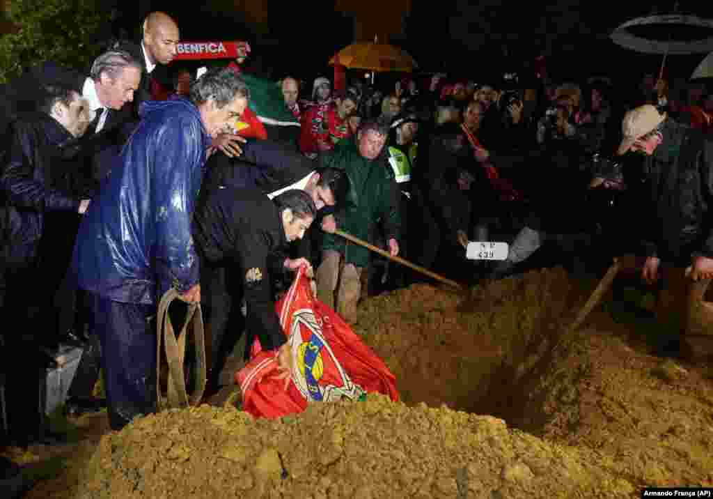 O ex-jogador do Benfica Rui Costa, ao centro, deposita uma bandeira do clube por cima do caixão de Eusébio, que foi a enterrar no cemitério do Lumiar, em Lisboa, a 6 de Janeiro de 2014. Ao lado estão o treinador do clube Jorge Jesus, e o capitão Luisão. (AP Photo/Armando Franca)