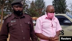 FILE Paul Rusesabagina is escorted in handcuffs into a courtroom, in Kigali, Rwanda October 20, 2020. He was released from prison on Friday, Mar. 24, 2023 and has left Rwanda for settlement in the United States.