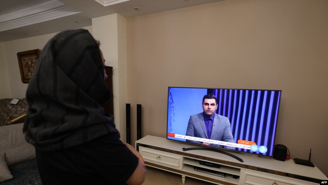 Seorang wanita Iran di Teheran menonton saluran TV berita Iran, yang meliput berita serangan Iran terhadap Israel, Minggu, 14 April 2024. (Foto: Atta Kenare/AFP)