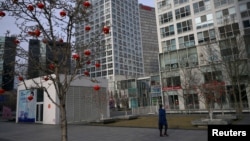 疫情期间，一位戴口罩的女性在北京市中心商业区一座商业大楼前走过。（2020年2月18日）