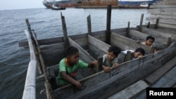 Anak-anak menggunakan toilet dari kayu di daerah kumuh dekat pelabuhan Jakarta Utara. (Foto: Reuters/Beawiharta)