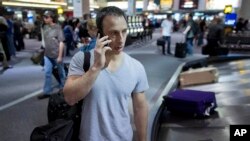 Seorang penumpang menelepon saat mengambil bagasinya di Bandara Internasional McCarran International di Las Vegas. (AP/Julie Jacobson)