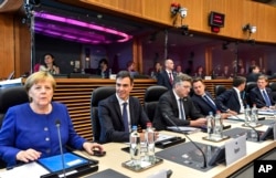 German Chancellor Angela Merkel, left, along with other EU leaders, attends a roundtable meeting at an informal EU summit on migration at EU headquarters in Brussels, June 24, 2018.