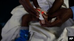 FILE - A doctor puts a heart monitor on the foot of a baby who is suffering from severe malaria in the Siaya hospital in western Kenya.