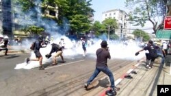 Imagen sacada de un video de manifestantes en Rangún, Myanmar, luchando contra gases lagrimógenos lanzados por las fuerzas de seguridad el 1 de marzo de 2021.