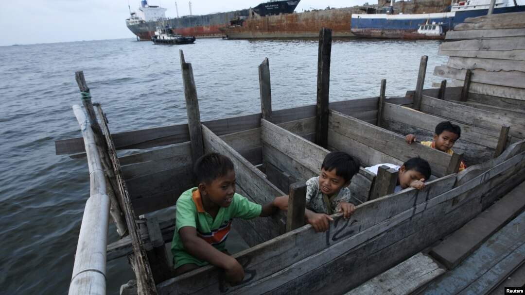 Anak-anak memakai WC umum di atas laut di daerah kumuh dekat pelabuhan Jakarta. (Foto: Reuters/Beawiharta)