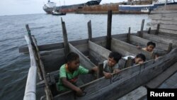 Anak-anak memakai WC umum di atas laut di daerah kumuh dekat pelabuhan Jakarta. (Foto: Reuters/Beawiharta)