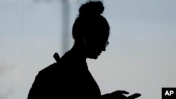 FILE - A woman checks her smartphone in Orem, Utah, Nov. 14, 2019.