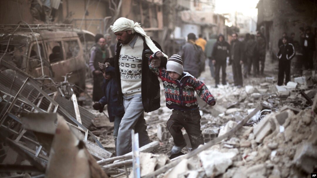 FILE - Seorang ayah dan anak-anaknya bergandengan tangan berusaha berjalan di antara puing-pung di Ghouta Timur, Suriah. (Foto: dok.)