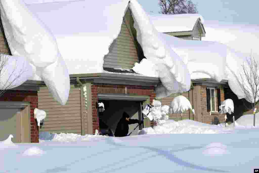 Snowdrifts create a beautiful setting as a man tries to dig out his driveway on Bowen Rd in Lancaster, N.Y. A lake-effect snow storm dumped over five feet of snow in areas across Western New York. Another two to three feet of snow is expected in the area, bringing snow totals to over 100 inches, almost a years&#39; worth of snow in three days.