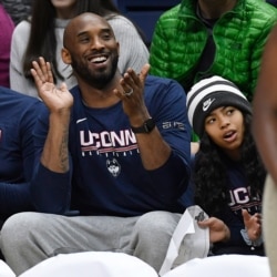 FILE - Kobe Bryant and his daughter Gianna watch the first half of an NCAA college basketball game between Connecticut and Houston, March 2, 2019, in Storrs, Conn.