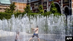 People play and refresh themselves in a fountain at the Museumplein square in Amsterdam, July 25, 2019, during the heat wave. 