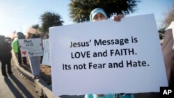 A woman who asked not to be identified holds a sign as she joins hundreds of supporters outside the Curtis Culwell Center where a Muslim conference against terror and hate was scheduled, Jan. 17, 2015, in Garland, Texas.