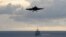 An F/A-18F Super Hornet from the Diamondbacks of Strike Fighter Squadron (VFA) 102, top, approaches to land on the flight deck of the aircraft carrier USS George Washington (CVN 73) while the Ticonderoga-class guided-missile cruiser USS Antietam (CG 54) t