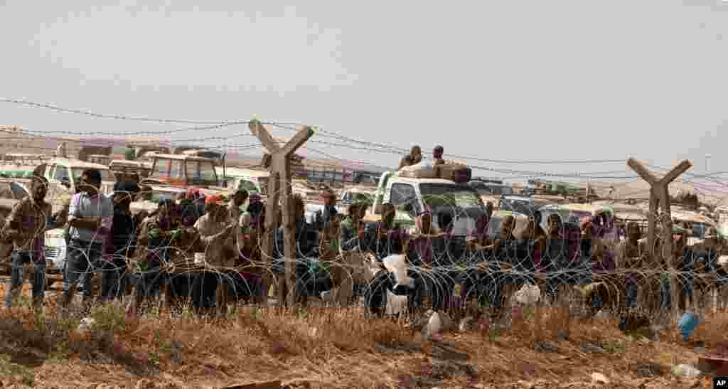 Syrian refugees wait for permission to enter Turkey at Yumurtalik crossing gate near Suruc, Turkey, Sept. 24, 2014.