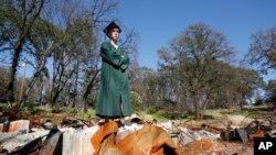 Sean Newsom, a senior at Paradise High School, poses in his cap and gown at the burned out ruins of his home in Paradise, Calif., June 5, 2019.