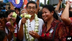 Senior member of National Rescue Party Prince Sisowath Thomico, center, poses for photographs with villagers during his visit to Boeung Kak lake, in Phnom Penh, Aug. 5, 2013.