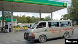 A minivan used for public transportation drives past a gasoline station in Port-au-Prince, Feb. 8, 2015.