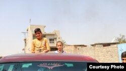 Noeh Binoo and his sister cheer from the back of a truck while returning to their home three years after the Islamic State takeover, August 2017. (Open Doors USA photo)