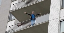 An apartment resident cheers her neighbors on as they sing and dance to lift the community's spirits while in isolation, Bethesda, Maryland.