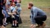 Britain&#39;s Prince Harry looks on as his wife Meghan, Duchess of Sussex, is hugged by Luke Vincent, 5, on their arrival in Dubbo, Australia.