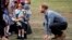 Britain&#39;s Prince Harry looks on as his wife Meghan, Duchess of Sussex, is hugged by Luke Vincent, 5, on their arrival in Dubbo, Australia.