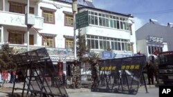 In this photo taken on Monday, Feb. 27, 2012, Chinese paramilitary police and riot police stand guard near barricades set up along the main street of Ngaba.