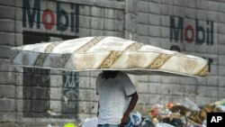 Un hombre camina con un colchón sobre su cabeza en Puerto Príncipe, Haití, el 27 de octubre de 2021. 