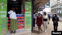 Pedestrians walk past an M-Pesa shop in downtown Nairobi, Kenya, May 12, 2009. 