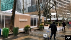 FILE - People walk by a Facebook “pop-up” trailer in New York’s Bryan Park, part of a one-day public event with Facebook employees answering questions about privacy settings and other issues, Dec. 13, 2018. 