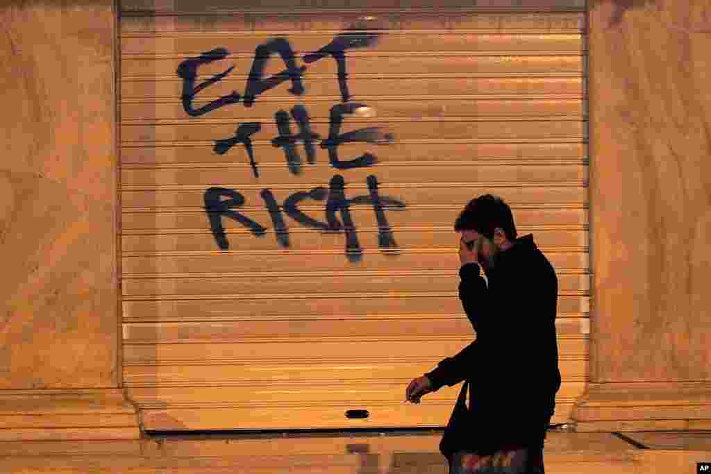 A passerby reacts to the effect of tear gas during clashes between protesters and riot police in Athens.  (AP)