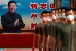 FILE - Paramilitary police officers march in formation near a poster of Chinese President Xi Jinping at the gate to the Forbidden City, in Beijing, China, May 22, 2020.