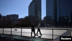 Para pejalan kaki mengenakan masker berjalan di jembatan di Zhongguancun, pusat teknologi di Beijing, di tengah wabah virus korona jenis baru yang melanda China, 17 Februari 2020. (Foto: Reuters)