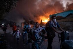 Migrants flee from the Moria refugee camp during a second fire, on the northeastern Aegean island of Lesbos, Greece, Sept. 9, 2020.