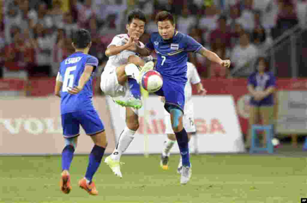 Ko Oo Ye of Myanmar, second left, and Thitipan Puangjan of Thailand, right, vie for the ball during the soccer final match at the SEA Games in Singapore, Monday, June 15, 2015. (AP Photo/Joseph Nair)