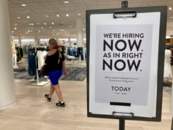 FILE - A customer walks behind a sign at a Nordstrom store seeking employees in Coral Gables, Fla., May 21, 2021.