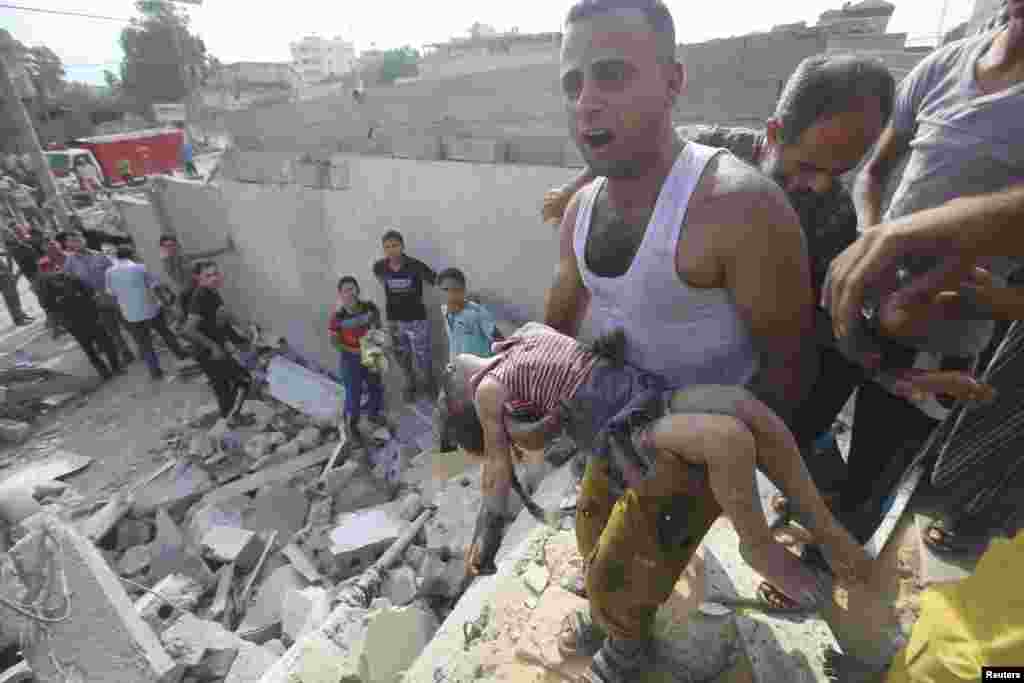 A Palestinian man carries the body of Palestinian girl killed in an Israeli airstrike in Khan Younis, in the southern Gaza Strip, July 29, 2014.