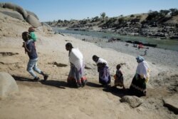 FILE - Ethiopians who have just crossed a river from Ethiopia to Sudan to flee from the Tigray region, walk towards the Hamdeyat refugees transit camp, which houses refugees fleeing the fighting, on the border in Sudan, Dec. 1, 2020.