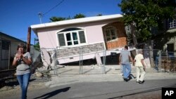 Residents survey damage where a home partially collapsed after an earthquake hit Guanica, Puerto Rico, Jan. 6, 2020.