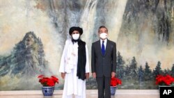 En esta foto de archivo del 28 de julio de 2021, publicada por la Agencia de Noticias Xinhua de China, el cofundador de los talibanes, el mulá Abdul Ghani Baradar, a la izquierda, y el ministro de Relaciones Exteriores de China, Wang Yi.