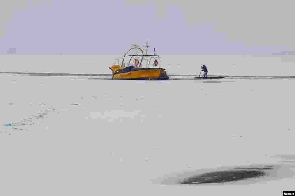 A man breaks ice to move his boat on the partially frozen Dal lake in Srinagar, Indian-administered Kashmir.