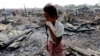 A woman walks among debris after fire destroyed shelters at a camp for internally displaced Rohingya Muslims in the western Rakhine State near Sittwe, Myanmar. 